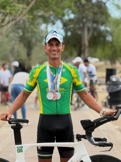 André Fuly com medalhas no pódio, ao lado da bicicleta